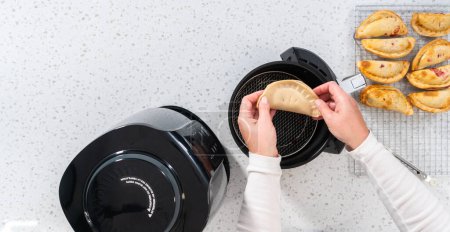 Photo for Flat lay. Frying sweet cherry empanadas in the air fryer. - Royalty Free Image