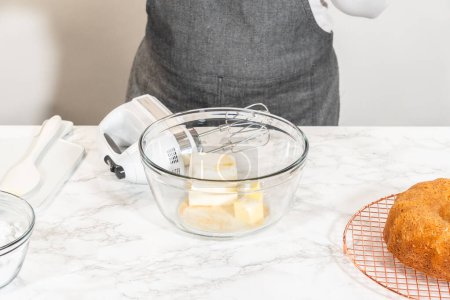 Téléchargez les photos : Dans un grand bol à mélanger, les ingrédients sont savamment mélangés pour créer une crème au beurre au fromage à la crème délectable pour le gâteau Bundt aux carottes. - en image libre de droit