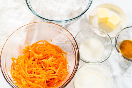 Photo for The measured ingredients are placed in mixing bowls on the counter, preparing to bake a scrumptious Carrot Bundt Cake from a cake mix. - Royalty Free Image