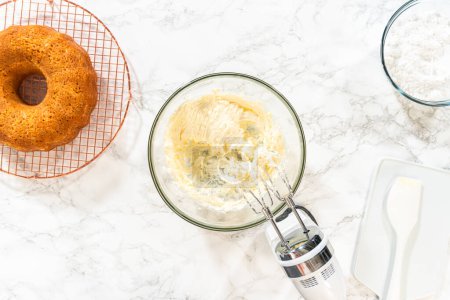 Foto de En un tazón grande, los ingredientes se mezclan expertamente para crear una deliciosa crema de mantequilla de queso crema para el pastel de zanahoria Bundt. - Imagen libre de derechos