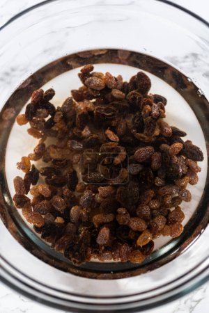 Téléchargez les photos : Tremper les raisins secs dans l'eau chaude pour faire cuire le mini pain de Pâques kulich. - en image libre de droit