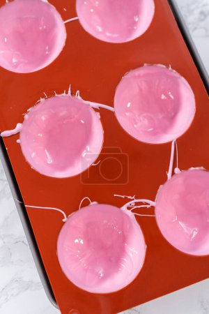 Photo for Filling in silicone chocolate molds with melted pink chocolate to prepare hot chocolate bombs. - Royalty Free Image