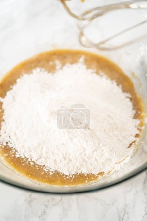 Photo for Mixing ingredients in a large glass mixing bowl to bake banana oatmeal muffins. - Royalty Free Image