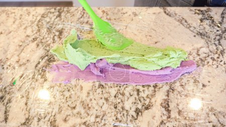 Foto de En una cocina bien iluminada, un surtido de glaseado de crema de mantequilla en varios tonos de verde y otros colores se mezcla meticulosamente y se prepara para la decoración artística de cupcakes en encantador - Imagen libre de derechos