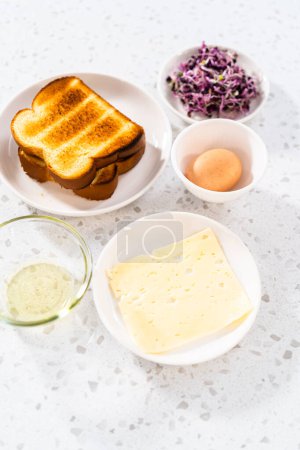 Téléchargez les photos : Ingrédients mesurés dans des bols à mélanger en verre pour faire un sandwich aux œufs et germes de petit déjeuner. - en image libre de droit