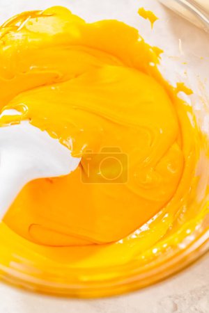 Téléchargez les photos : Mélange de colorants alimentaires orange et jaune dans du chocolat fondu pour préparer du caramel au maïs.. - en image libre de droit