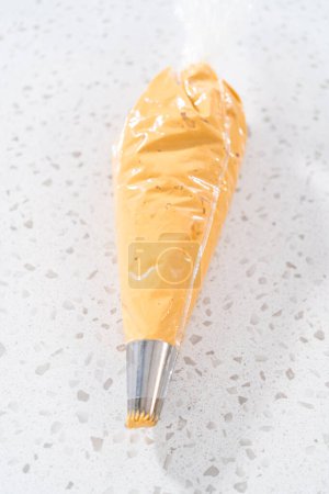 Foto de Transferencia de glaseado de crema de mantequilla dulce de leche recién batida en una bolsa de tuberías. - Imagen libre de derechos