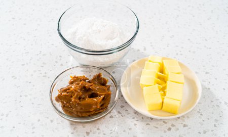 Téléchargez les photos : Ingrédients mesurés dans des bols à mélanger en verre pour faire du glaçage à la crème de beurre dulce de leche. - en image libre de droit