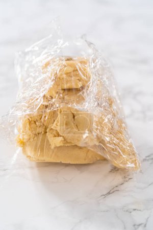 Photo for Wrapping cookie dough into cellophane wrap to transfer into the refrigerator for chilling. - Royalty Free Image