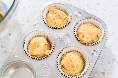 Photo for Scooping cupcake batter with dough scoop into a baking cupcake pan with liners to bake dulce de leche cupcakes. - Royalty Free Image