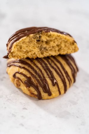 Photo for Freshly baked banana cookies with chocolate drizzle on a kitchen counter. - Royalty Free Image