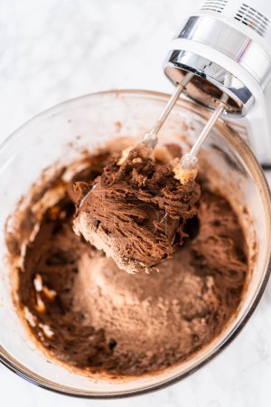 Foto de Mixing ingredients with a hand mixer to bake chocolate cookies with chocolate hearts for Valentines Day. - Imagen libre de derechos