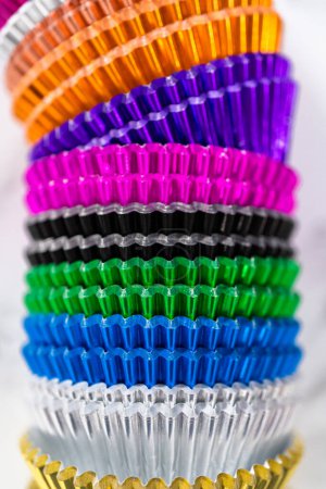 Foto de Vista de cerca. Tazas de forro de lámina multicolor para cupcakes en una encimera de mármol. - Imagen libre de derechos