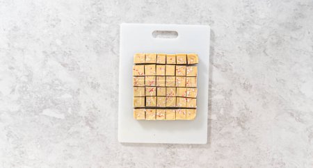 Photo for Flat lay. Cutting candy cane fudge with a large kitchen knife into square pieces on a white cutting board. - Royalty Free Image