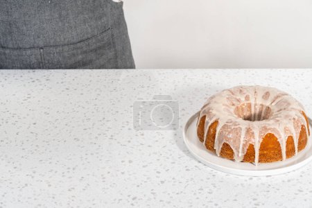 Photo for Freshly baked simple vanilla bundt cake with a white glaze on a serving plate. - Royalty Free Image