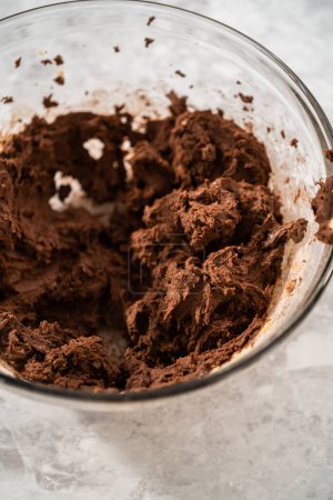 Téléchargez les photos : Mélanger les ingrédients dans un grand bol de mélange en verre avec un mélangeur de cuisine pour cuire des biscuits au chocolat avec des copeaux de menthe poivrée. - en image libre de droit