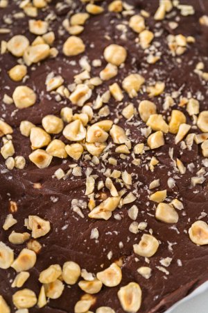 Photo for Removing chocolate hazelnut fudge from a square cheesecake pan lined with parchment. - Royalty Free Image