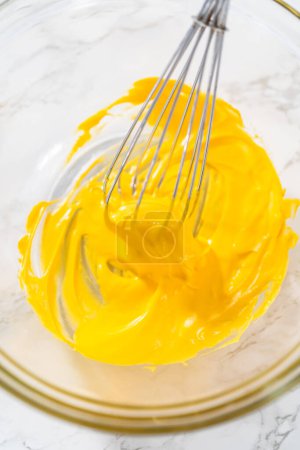 Foto de Mezcla de colorante de alimentos amarillos en el merengue para hornear galletas de merengue de Pascua. - Imagen libre de derechos
