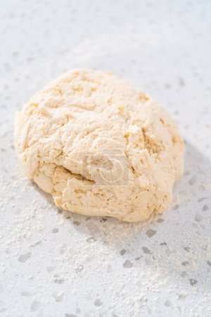 Foto de Rolling masa de pan con un rodillo francés para hornear naan dippers. - Imagen libre de derechos