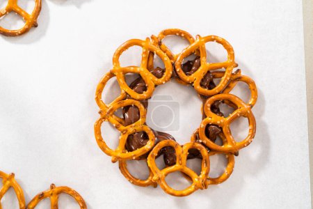 Foto de Dipping pretzels twists into melted chocolate to make a chocolate pretzel Christmas wreath. - Imagen libre de derechos