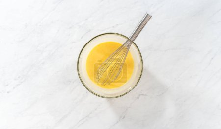 Foto de Acostado. Mezclar ingredientes húmedos en un tazón de vidrio grande para hornear pastel de paquete de arándanos limón. - Imagen libre de derechos