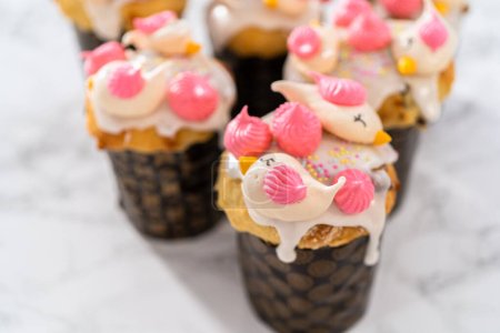 Photo for Freshly baked mini Easter bread kulich with lemon glaze, decorated with sprinkles and meringue bird-shaped cookies. - Royalty Free Image