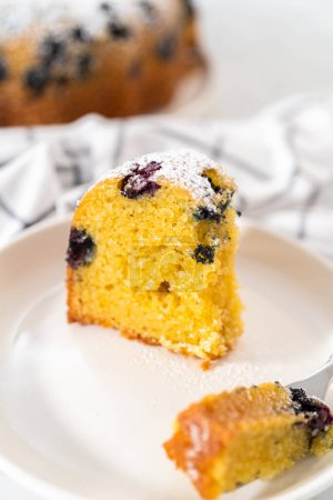 Photo for Slicing freshly baked lemon blueberry bundt cake with powdered sugar dusting. - Royalty Free Image
