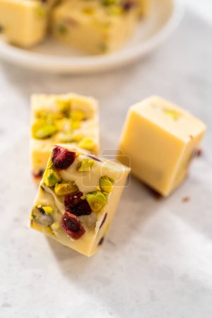 Téléchargez les photos : Pièces carrées de caramel à la pistache aux canneberges fait maison sur un comptoir de cuisine. - en image libre de droit