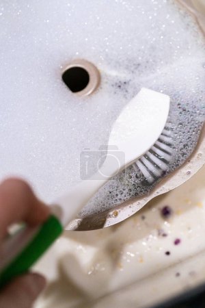 Foto de Fregar la bandeja de torta de paquete de aluminio sucio con cepillo de fregadero de cocina. - Imagen libre de derechos