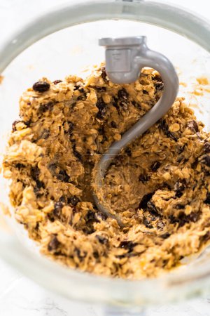 Photo for Mixing ingredients in a kitchen stand mixer to bake soft oatmeal raisin walnut cookies. - Royalty Free Image