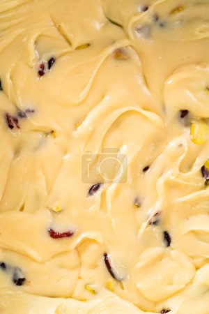Foto de Llenado cuadrado de tarta de queso forrada con papel pergamino con mezcla de caramelo para preparar dulce de pistacho de arándano. - Imagen libre de derechos