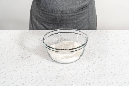Téléchargez les photos : Mélanger les ingrédients secs avec un fouet à la main dans un grand bol à mélanger en verre pour cuire des cupcakes dulce de leche. - en image libre de droit