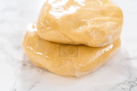 Téléchargez les photos : Emballage de pâte à biscuits dans une pellicule de cellophane à transférer au réfrigérateur pour le refroidissement. - en image libre de droit