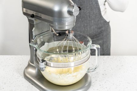 Foto de Azotar los ingredientes en una batidora eléctrica para hacer glaseado de crema de mantequilla dulce de leche. - Imagen libre de derechos