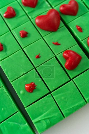 Téléchargez les photos : Décoration de morceaux carrés de caramel vert avec des cœurs rouges chocolat. - en image libre de droit