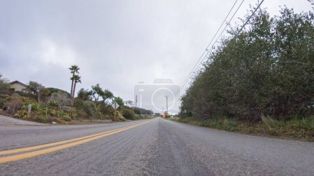 Téléchargez les photos : Le véhicule parcourt les rues de Morro Bay, en Californie, par une journée nuageuse d'hiver. L'atmosphère est maussade et sereine alors que le ciel couvert jette une lumière douce sur les charmants bâtiments et le calme - en image libre de droit