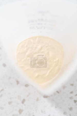 Foto de Chips de chocolate derretido en una taza de inmersión de silicona para hacer barras de pretzel cubiertas de chocolate de bastón de caramelo. - Imagen libre de derechos