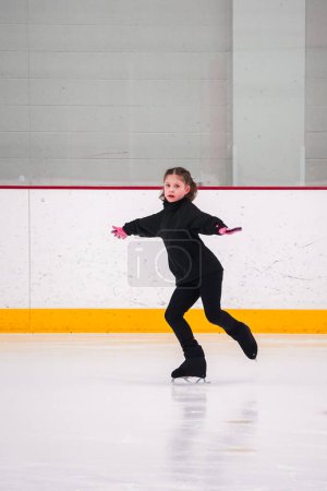 Photo for Little girl practicing figure skating at the indoor ice rink. - Royalty Free Image