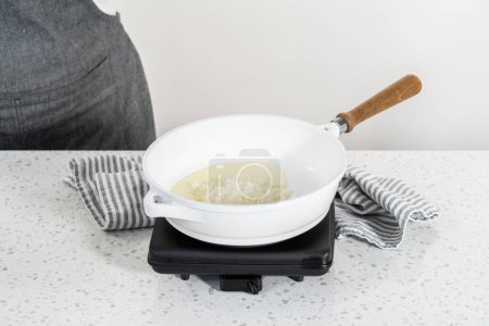 Téléchargez les photos : Faire frire l'oignon sur une poêle antiadhésive pour faire des empanadas petit déjeuner avec des œufs et des patates douces. - en image libre de droit