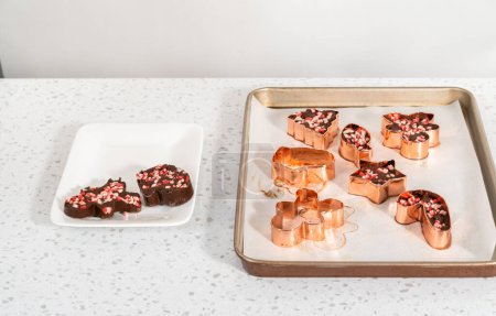 Téléchargez les photos : Enlever le caramel à la menthe poivrée fraîchement confectionné des coupeuses à biscuits. - en image libre de droit