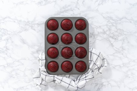 Photo for Flat lay. Cooling freshly baked red velvet cupcakes on a kitchen counter. - Royalty Free Image