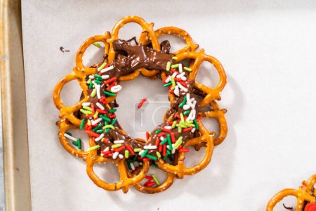 Téléchargez les photos : Dipping pretzels twists into melted chocolate to make a chocolate pretzel Christmas wreath. - en image libre de droit