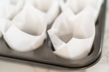 Téléchargez les photos : Doublure plaque de cuisson cupcake avec doublures de tulipes en papier pour cuire sans levure cupcakes rouleau de cannelle. - en image libre de droit