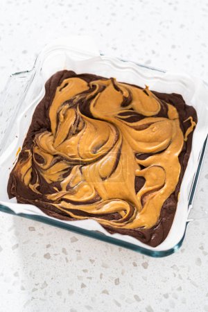 Téléchargez les photos : Removing chocolate fudge with peanut butter swirl from the baking pan lined with parchment - en image libre de droit