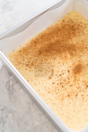 Téléchargez les photos : Verser le mélange de caramel dans le moule à gâteau au fromage carré doublé de papier parchemin pour préparer le caramel au lait de poule. - en image libre de droit