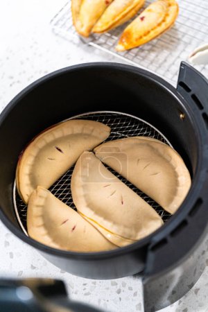 Téléchargez les photos : Faire frire des empanadas de cerises douces dans la friteuse. - en image libre de droit