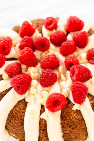 Photo for With precision, the White Chocolate Raspberry Bundt Cake is carefully removed from the pan - adorned with luscious cream cheese frosting, creating a delectable treat that is sure to delight. - Royalty Free Image