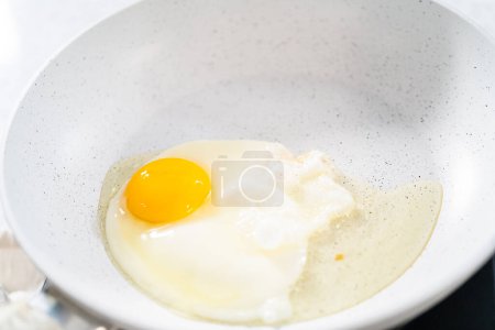 Foto de Freír los huevos en una sartén antiadherente para hacer el huevo del desayuno y brotar sándwich. - Imagen libre de derechos