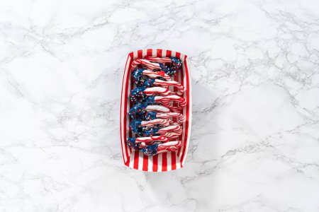 Téléchargez les photos : Flat lay. American flag. Red, white, and blue chocolate-covered pretzel twists. - en image libre de droit