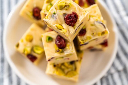 Photo for Homemade cranberry pistachio fudge square pieces on a white plate. - Royalty Free Image